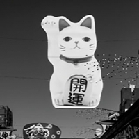Cat sculpture with mandarin lettering hanging from wires above street