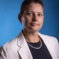 Professor Caro De Robertis in an off-white blazer, back top, and heavy chain necklace.