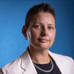 Professor Caro De Robertis in an off-white blazer, black t-shirt, and heavy silver chain