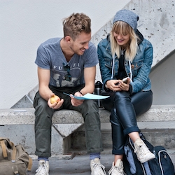 Man and Woman sitting together outside looking at paper and smiling