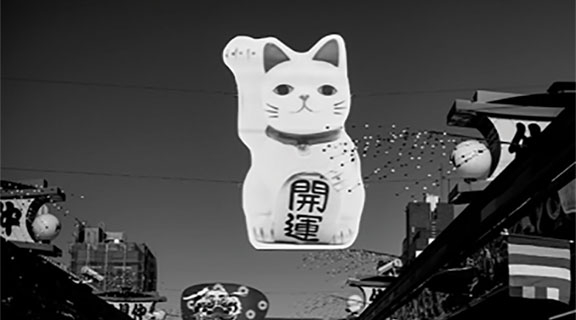 Cat sculpture with mandarin lettering hanging from wires above street
